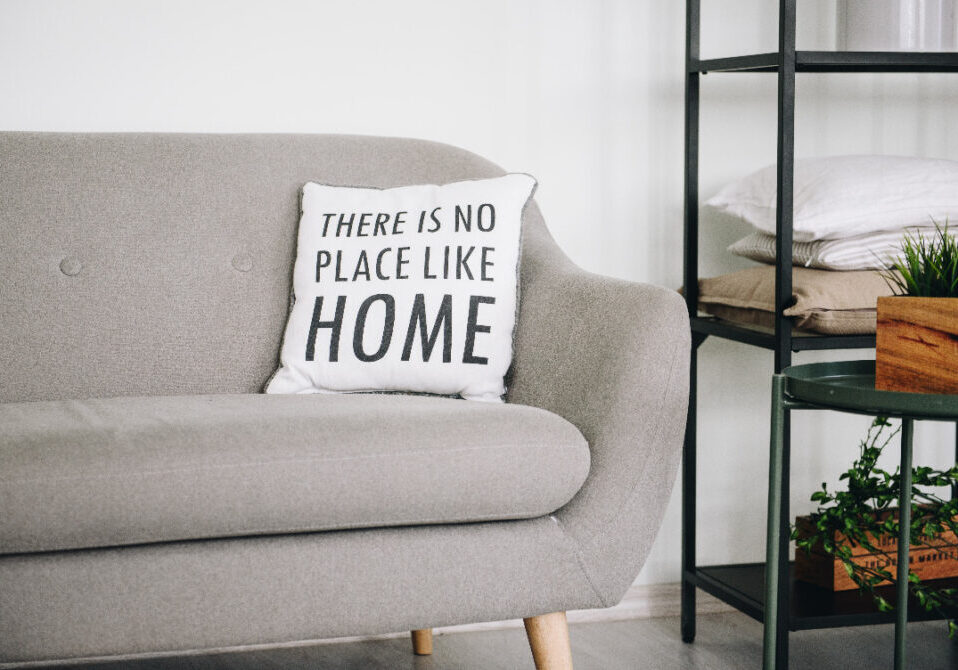 Comfortable couch with pillow that reads, "There is no place like home."